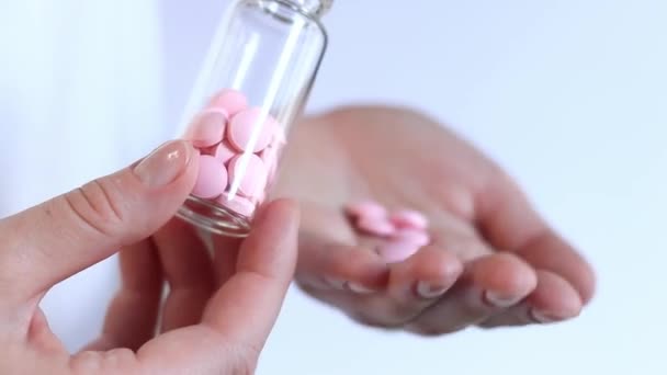 Pastillas. Vitaminas rosadas en una botella de vidrio. Vierte vitaminas en la palma de tu mano. El concepto de medicina, salud y abuso de drogas. Epidemia, analgésicos, atención médica, píldoras medicinales - Metraje, vídeo