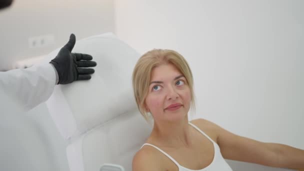 Młoda kaukaska kobieta leżąca na kanapie do badania lekarskiego w nowoczesnym gabinecie lekarskim - Materiał filmowy, wideo
