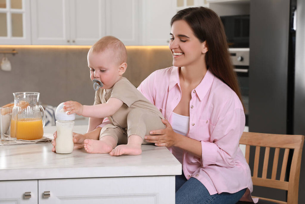 Happy young woman with her cute little baby in kitchen - Photo, image
