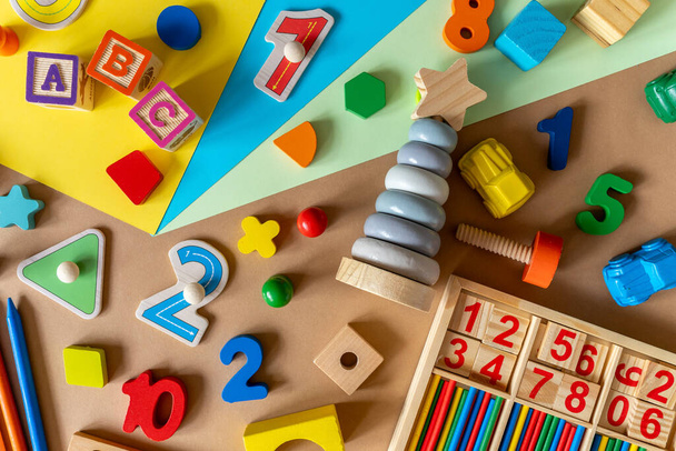 Drewniane zabawki dla dzieci na kolorowym papierze. Bloki zabawek edukacyjnych, piramida, ołówki, liczby. Zabawki do przedszkola, przedszkola lub przedszkola. widok z góry, zbliżenie - Zdjęcie, obraz