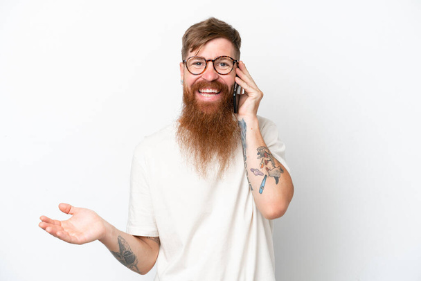 Rotschopf mit langem Bart isoliert auf weißem Hintergrund hält ein Gespräch mit dem Mobiltelefon mit jemandem - Foto, Bild