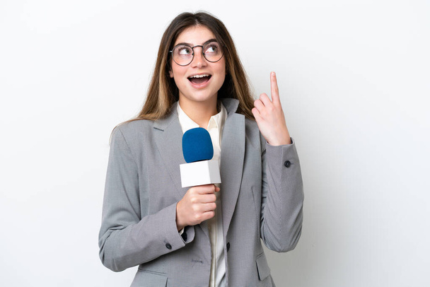 Young caucasian TV presenter woman isolated on white background thinking an idea pointing the finger up - 写真・画像