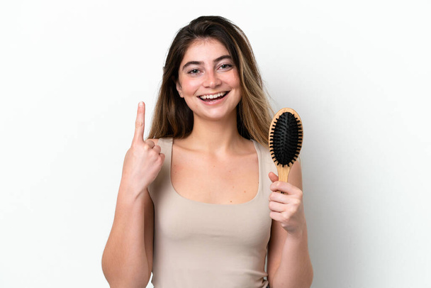 Νεαρή γυναίκα με χτένα μαλλιών απομονωμένη σε λευκό φόντο που δείχνει μια μεγάλη ιδέα - Φωτογραφία, εικόνα