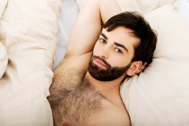Muscular man lying in bed. - Zdjęcie, obraz