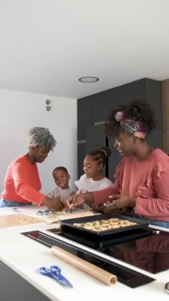 African family cutting cookie shapes in a cookie dough in the kitchen. Horizontal extended family. - Footage, Video