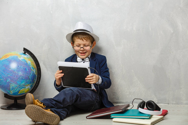 Little schoolboy having fun with his tablet. - Foto, Imagen