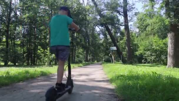 El chico se cae cuando monta un scooter eléctrico. Montar un e-scooter sin equipo de protección. Mayor riesgo de lesiones al utilizar vehículos alimentados con baterías. Concepto de problemas para garantizar la seguridad al conducir - Imágenes, Vídeo