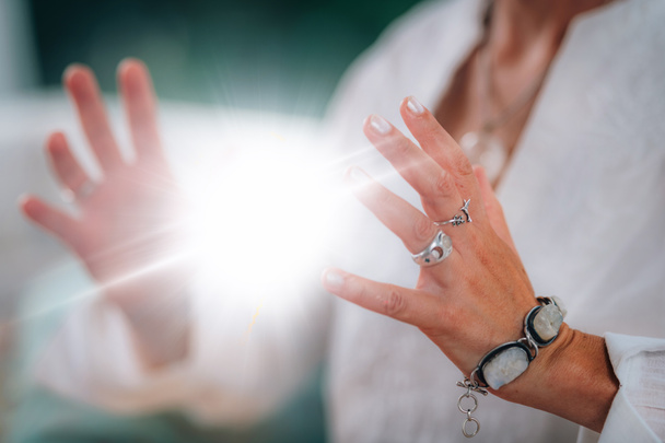 霊的なエネルギーを放射する. スピリチュアルな教師は,彼女の手の間に明るく輝くエネルギーボールを放射し,彼女の深い精神的なつながりと癒しの能力を示しています. - 写真・画像