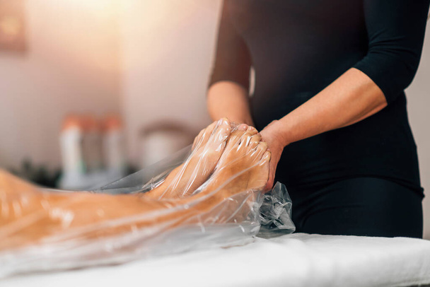 Tratamiento anticelulitis adelgazante al vacío con una bolsa de nylon para las piernas. Cliente femenino acostado en una mesa de masaje en un centro de bienestar de belleza. - Foto, Imagen