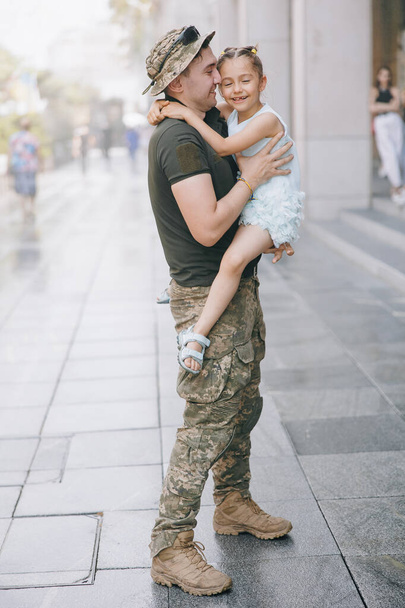 A háborúból hazatérő ukrán katona találkozik kislányával, és örömmel öleli át. Háború Ukrajnában. Orosz katonai invázió Ukrajnában. Háború és gyermekek. - Fotó, kép