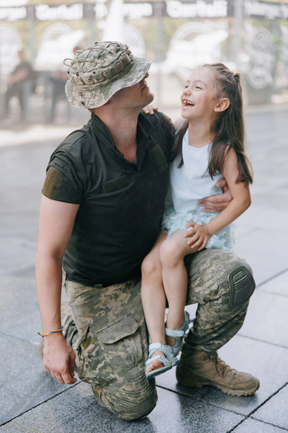 Petite fille ukrainienne rencontre son père de la guerre pendant ses vacances et joue joyeux avec lui. Guerre en Ukraine. Invasion militaire russe en Ukraine. Guerre et enfants. - Photo, image
