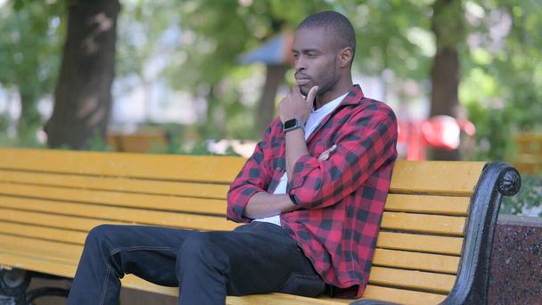 Vakava nuori afrikkalainen mies istuu ulkona - Valokuva, kuva