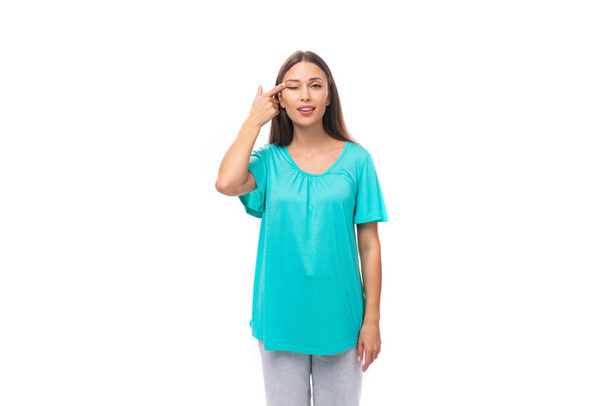 jong brunette europees dame met rechte haar gekleed in een blauw t-shirt bedekt haar oog met haar hand. - Foto, afbeelding