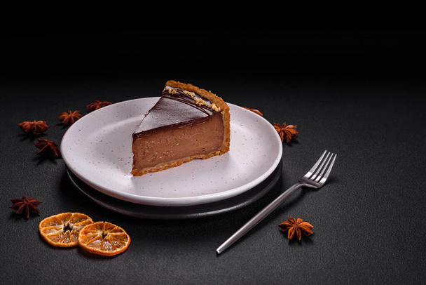 Delicious, fresh, sweet chocolate cake with nuts cut into slices on a dark concrete background - Photo, Image