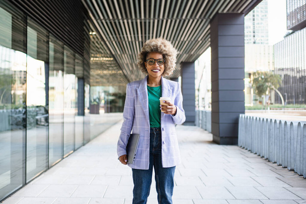 Portrait de jeune femme d'affaires afro-américaine en blazer et lunettes tendance debout sur le bureau de l'entreprise - Photo, image