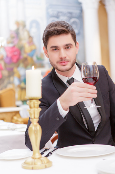 Man in suit raising his glass of wine - Фото, изображение