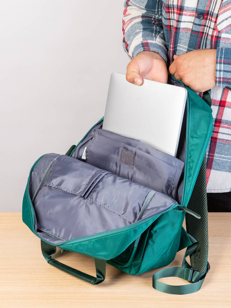 Gros plan d'un jeune étudiant qui sort un ordinateur portable d'un sac à dos. - Photo, image