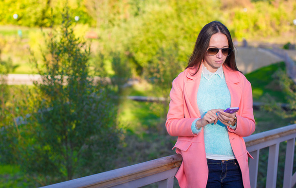 junge Frau mit ihrem Handy an einem Herbsttag - Foto, Bild