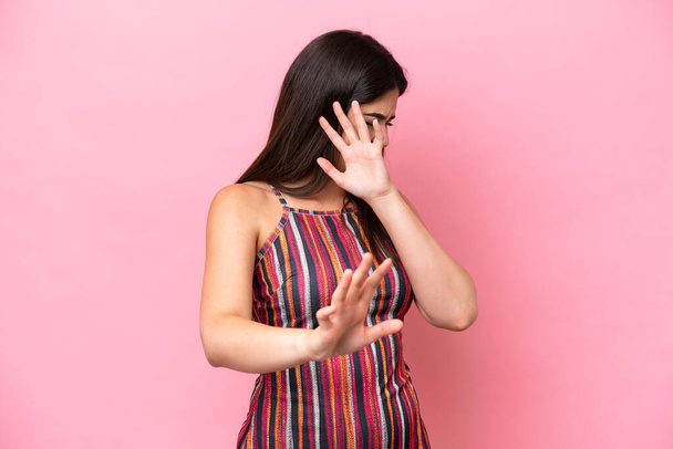Jeune femme brésilienne isolée sur fond rose nerveux étirement des mains à l'avant - Photo, image