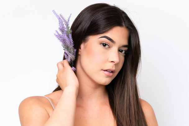 Young Brazilian woman isolated on white background holding a lavender plant. Close up portrait - Foto, afbeelding
