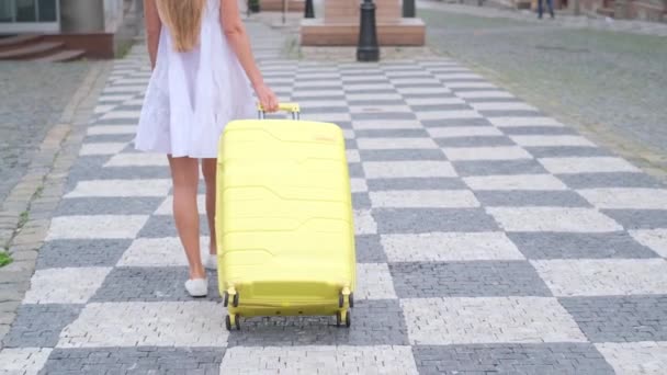 Een meisje loopt over de zebrapad met bagage. Concept van reizen, levensstijl. Langzame beweging. - Video