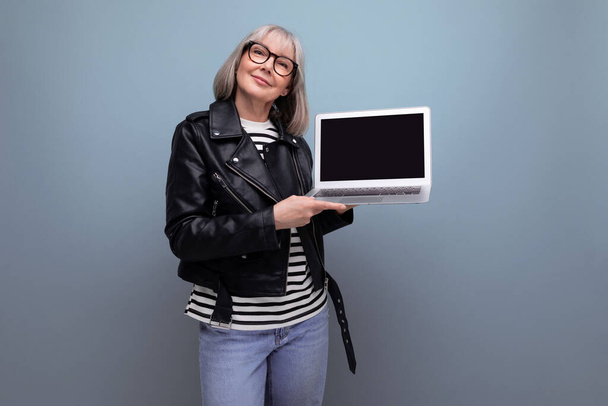 moderno anni 60 maturo vecchia signora freelance con capelli grigi naviga su internet utilizzando computer portatile con mockup su sfondo luminoso. - Foto, immagini