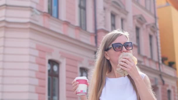 Ritratto di turista che mangia un croissant all'aperto. A una donna piace cucinare mentre viaggia. Rallentatore - Filmati, video