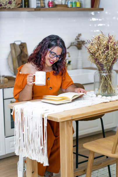 Γυναίκα εργάζεται για το βιβλίο της απολαμβάνοντας ένα φλιτζάνι καφέ - Φωτογραφία, εικόνα