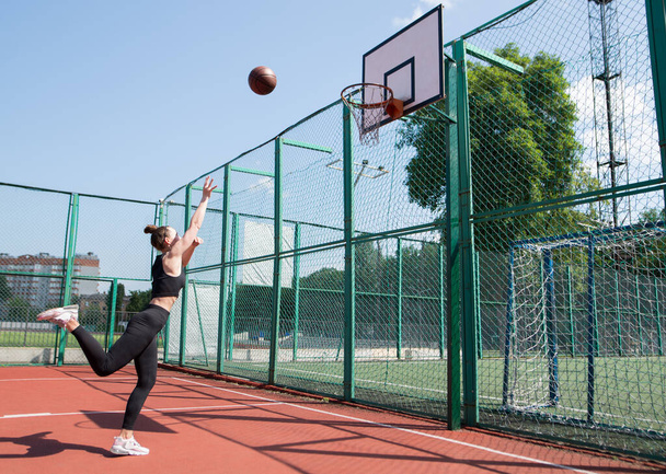 Спортивная баскетболистка бросает мяч в сетку. - Фото, изображение