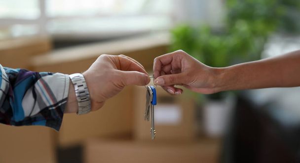 Nahaufnahme von männlichen und weiblichen Händen mit Schlüsseln aus dem neuen Haus. Paar mit Schlüsselanhänger. Kauf Wohnung, Umzug und Änderung des Wohnraumkonzeptes - Foto, Bild