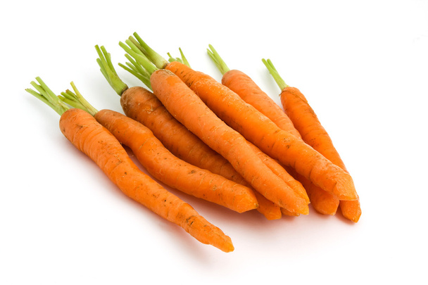 Куча органической моркови с зелеными верхушками на белом
 - Фото, изображение