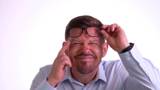 Young bearded man with eyes disease takes off glasses and squints trying to see objects. Disappointed male with myopia spreads hands in frustration - Footage, Video