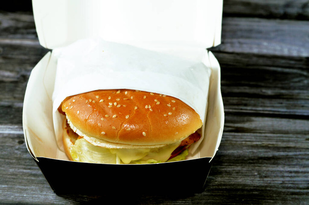Eine saftige doppelte Rindfleischpastete mit Käse mit Soße, knusprigem Salat, frischen Tomaten, Zwiebeln und Essiggurken in einem großen Sesamkernbrötchen, einem Burger-Sandwich mit speziellen Soßen - Foto, Bild