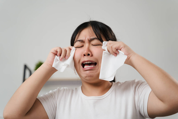 Portret smutnej Azjatki płaczącej wyciera łzy ręcznikiem z bibuły. - Zdjęcie, obraz