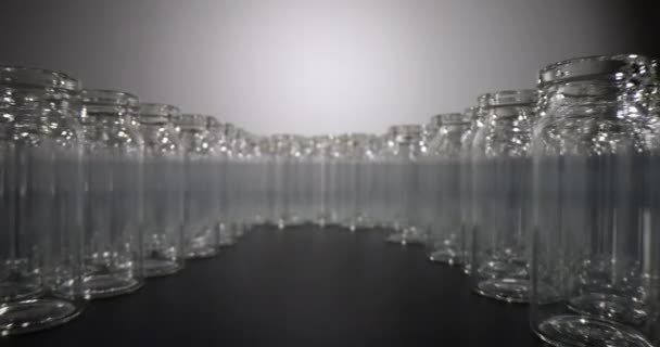Prázdné skleněné injekční lahvičky na vakcíny umístěné v kruhu. Transparentní láhve určené pro skladování léků a pro lékařské účely stojí na černém povrchu - Záběry, video