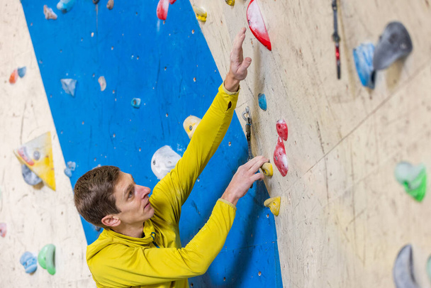 Junger Kletterer klettert Indoor-Wand, Sportkonzept - Foto, Bild