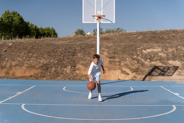 Молодий хлопчик грає в баскетбол на відкритому майданчику. Спортивна концепція. - Фото, зображення