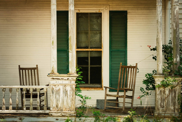 Time-φθαρμένη βεράντα και κουνιστή καρέκλα ματιά σε κατάφυτη αυλή - Φωτογραφία, εικόνα