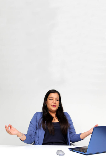40-year-old Latina woman breathes pranayama and practices yoga in her office to relax and de-stress from work pressure and prevent burnout - Valokuva, kuva