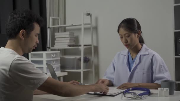Paciente masculino visita a doctora asiática discutiendo salud y medicina en clínica. - Metraje, vídeo