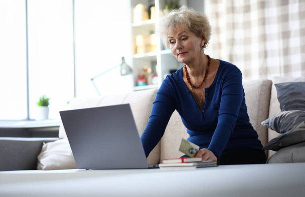Portrét staré ženy pracující doma na počítači. Podnikatelka platí za služby prostřednictvím internetu pomocí kreditní karty. Koncept nakupování a elektronických plateb online - Fotografie, Obrázek