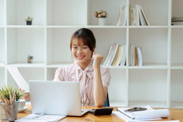 Веселий працівник святкує її досягнення, читаючи хороші новини на ноутбуці в офісі. - Фото, зображення