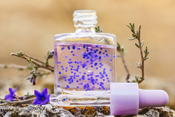 Cosmetic bottle with facial serum. Glass jar with a dropper. Purple cuticle oil with pellets has lavender scent. Beauty treatment concept. Anti aging products. Alternative medicine Copy space for text - Photo, Image