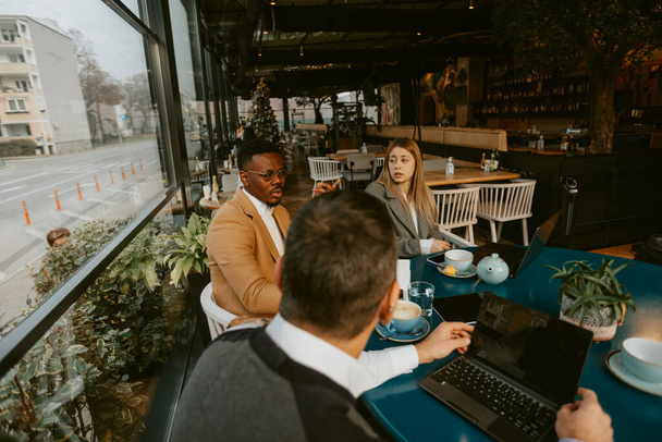 Три бізнесмени говорять про бізнес-плани, сидячи в кафе - Фото, зображення