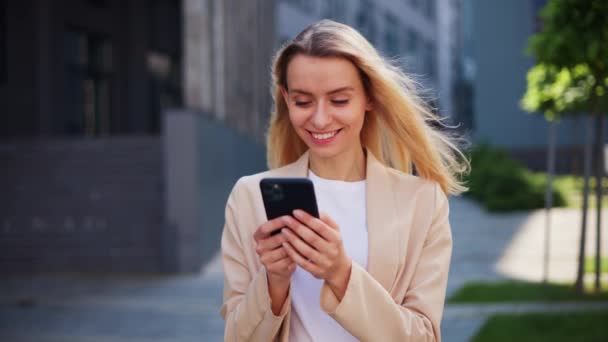 Chica alegre eficaz sosteniendo el teléfono inteligente utilizando la nueva aplicación para la red social - Metraje, vídeo