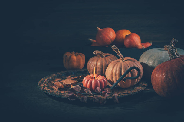 Herfst of herfst oogstconcept met pompoenen en kaarsen op donkere houten ondergrond - Foto, afbeelding