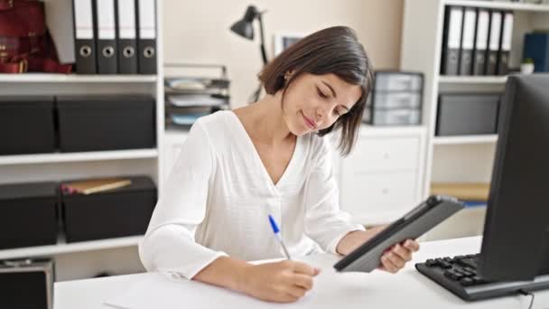Jeune belle hispanique femme d'affaires en utilisant touchpad écriture sur le document au bureau - Séquence, vidéo