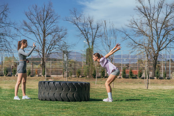 Tyttö harmaa urheiluvaatteet laskenta hänen ystävänsä, kun hän on hyppäämällä kuorma rengas - Valokuva, kuva