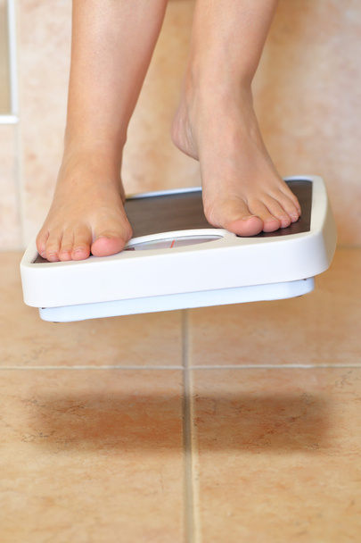 Woman's feet and bathroom scale hovers above the floor - Photo, Image