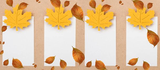 Decoratieve herfstblad en blanco papieren kaart voor tekstbericht op een bruine achtergrond. - Foto, afbeelding